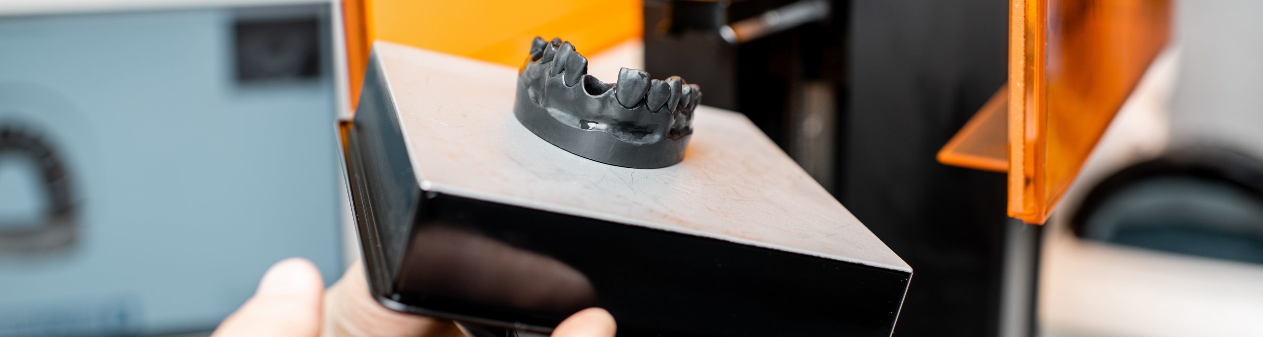 Dental technician removing jaw model from a 3d printer at the laboratory, modeling frame for implant production